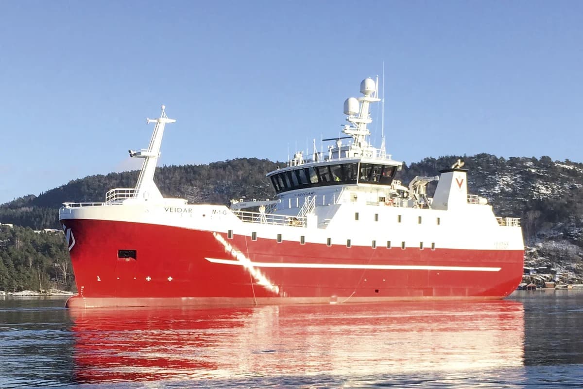 The longliner Veidar under way, red hull and white superstructure