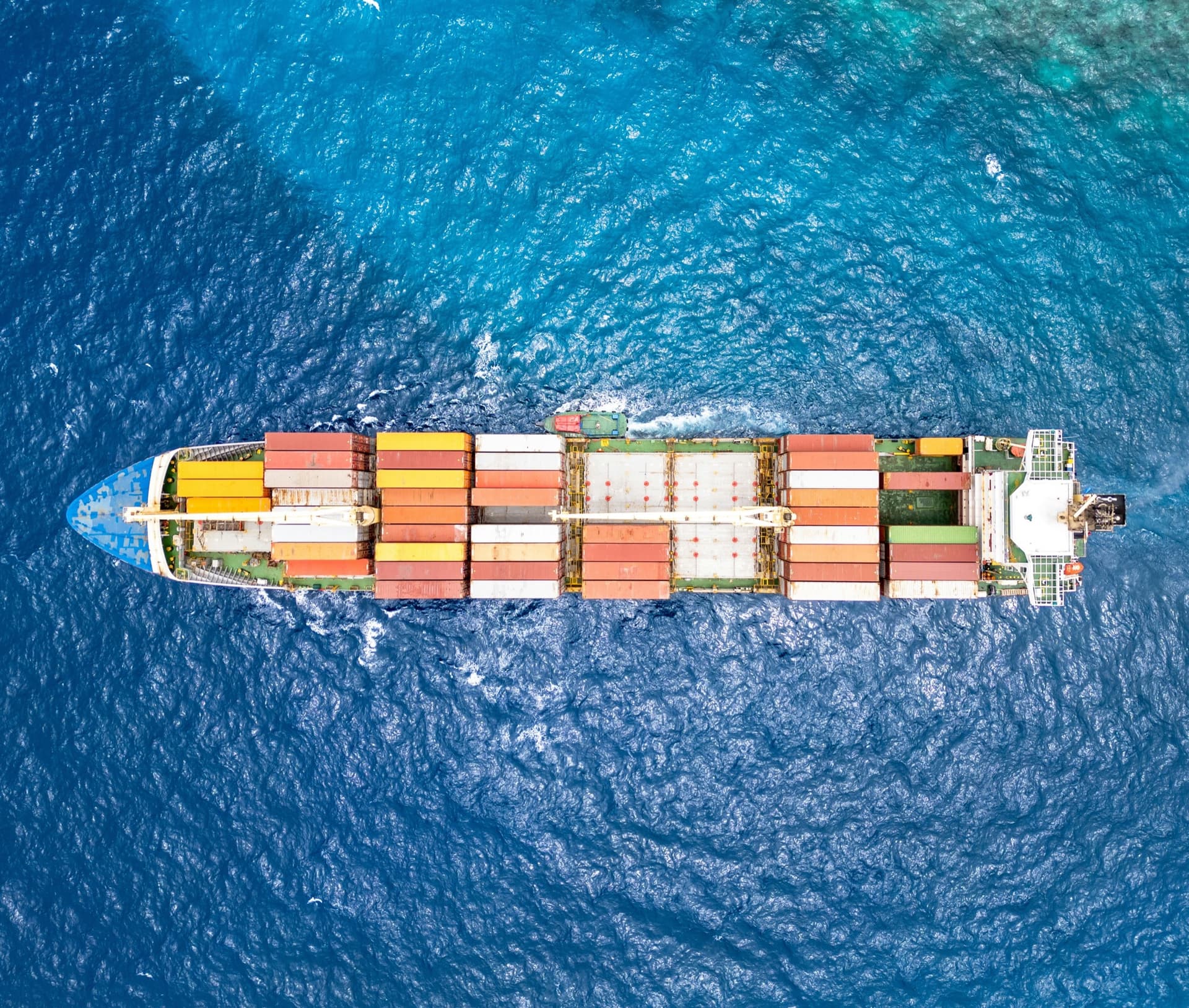 A container ship seen from above, under way on deep blue water